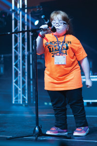 Hannah Lindner, 13, recipient of Childrens Miracle Network assistance, sings “Let it Go” from the movie Frozen at the 2014 Shockerthon held at Kansas Star Arena on November 22, 2014. (Kevin Brown/The Sunflower)