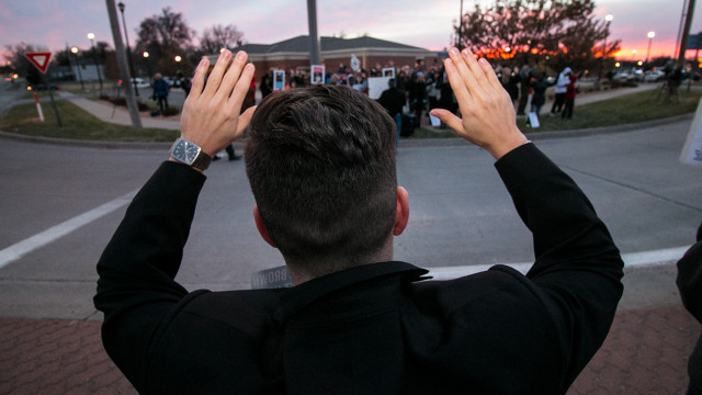 Wichita State School of Music professor Geoff Deibel holds his hands up with the crowd as they shout, "Hands up, don't shoot" Tuesday evening. Protestors gathered to highlight the issues with police in their own communities. (Kevin Brown/The Sunflower