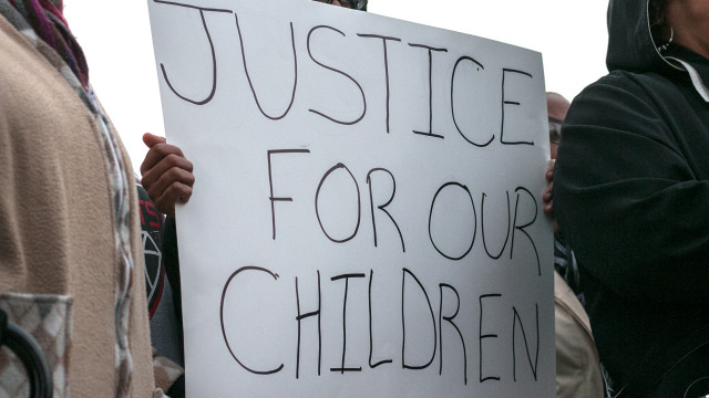 A protester holds a sign that reads “justice for our children” at a #NoFergusonHere protest and vigil near 21st Street and Hillside on November 31, 2014. (Kevin Brown/The Sunflower)